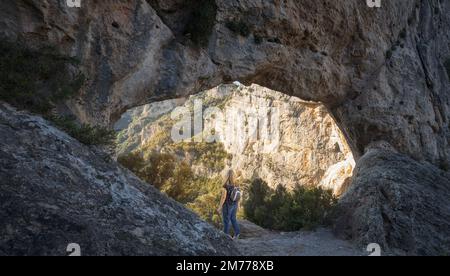 Femme regardant à travers l'Arche naturelle Forat de la Vella au Parc naturel de ports de Beseit, Catalogne Banque D'Images