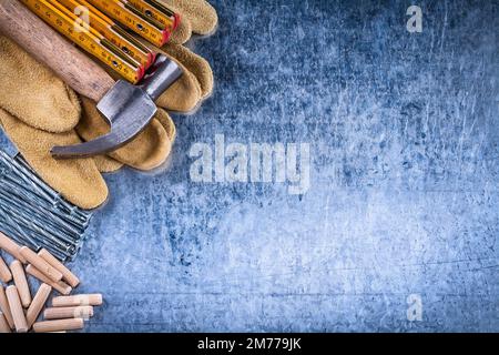 Gants de sécurité pour marteau à griffe tas de mètres en bois de clous et chevilles en acier inoxydable sur surface métallique rayée concept de construction de vue de dessus. Banque D'Images