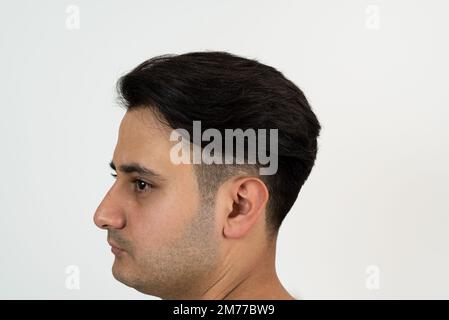 Portrait d'un homme à la peau brune avec des cheveux noirs soyeux bien entretenus sur un fond blanc isolé. Banque D'Images