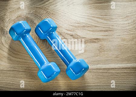 Paire de poids-haltères bleus sur une planche en bois concept de fitness. Banque D'Images