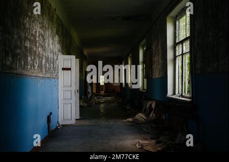 Un grand couloir sombre d'une école abandonnée, une école abandonnée ukrainienne. Banque D'Images