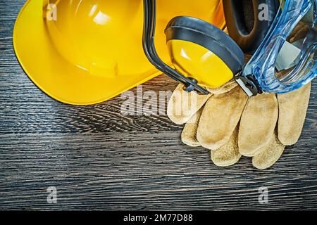 Gants de protection lunettes casque de construction casque sur panneau en bois. Banque D'Images