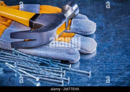 Ensemble de gants de sécurité pour clous de construction et marteau à griffe sur surface métallique rayée concept d'entretien. Banque D'Images