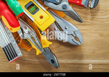 Jeu d'outils en ceinture à outils en cuir sur panneau en bois. Banque D'Images