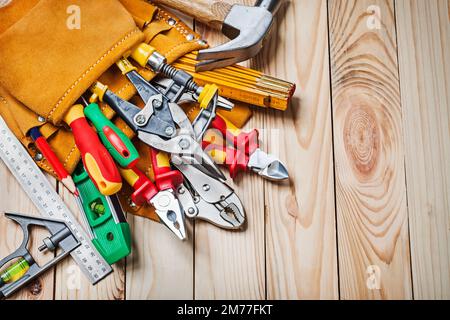 jeu d'outils dans une ceinture à outils sur fond en bois Banque D'Images