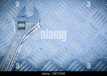 Clé réglable en acier inoxydable sur le concept de construction de plaque métallique à rainures. Banque D'Images