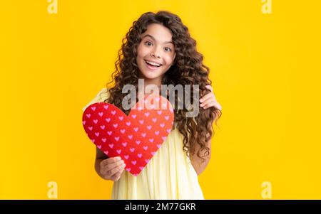 Joyeux portrait d'adolescent. Saint-Valentin. Rêvant enfant adolescent mignon avec coeur rouge. Fille souriante. Banque D'Images