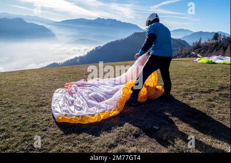 Homme sur une pente herbeuse préparer le planeur pour le parapente de Vetriolo terme, province de trente - Trentin Haut-Adige - école de parapente - Italie Banque D'Images