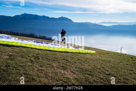 Homme sur une pente herbeuse préparer le planeur pour le parapente de Vetriolo terme, province de trente - Trentin Haut-Adige - école de parapente - Italie Banque D'Images