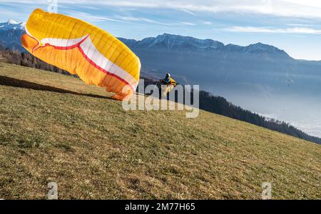 Homme sur une pente herbeuse préparer le planeur pour le parapente de Vetriolo terme, province de trente - Trentin Haut-Adige - école de parapente - Italie Banque D'Images