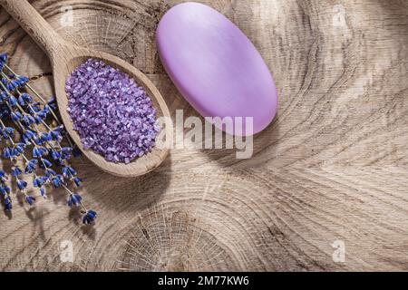 Cuillère en bois avec un morceau de savon de lavande séché au sel de mer sur planche de bois concept de soin spa. Banque D'Images