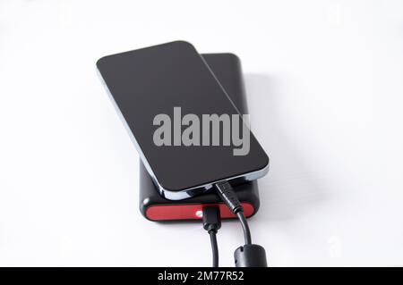 Smartphone et batterie auxiliaire avec chargeur sur la table blanche dans un bureau Banque D'Images