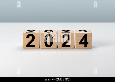 Nouvelle année 2024. Blocs de bois 2024 sur fond gris neutre. 2023 à 2024 sur un cube en bois pour la préparation du changement de nouvelle année et pour commencer de nouvelles affaires Banque D'Images