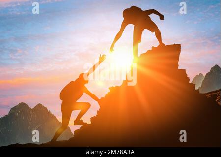 Concept d'aide et d'assistance. Silhouettes de deux personnes grimpant en montagne grâce à l'assistance mutuelle, au travail d'équipe et au partenariat. succès commercial Banque D'Images