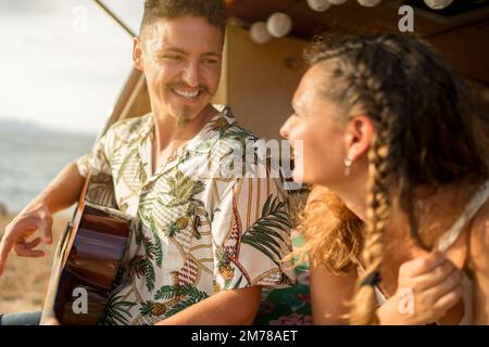 Gros plan d'un homme jouant de la guitare à côté d'une femme à l'intérieur d'une camionnette Banque D'Images