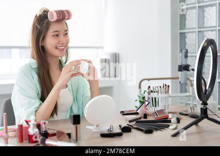 Beauté vlogger concept, jeune femme montrant pot de crème hydratante pour introduire le produit sur Vlog. Banque D'Images