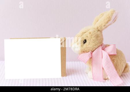 Maquette de Pâques cadre de carte de vœux blanc avec lapin sur fond de couverture rose. Banque D'Images