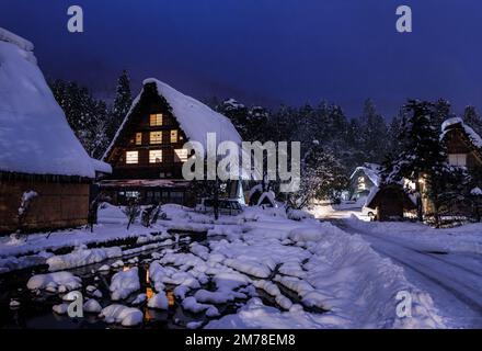 Ferme japonaise enneigée dans un village historique en bois la nuit Banque D'Images