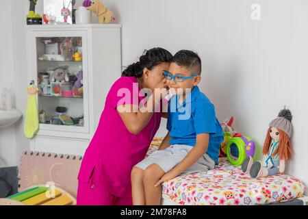 Médecin pédiatrique vérifiant l'oreille d'un enfant assis sur le lit au bureau. Banque D'Images