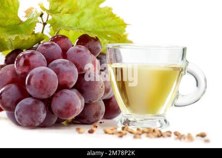 Huile de pépins de raisin sur fond blanc. L'image montre également des raisins clairs et des raisins foncés disposés sur un fond blanc Banque D'Images