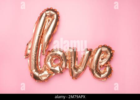 Ballons de feuillard rose pâle en forme de mot Amour avec coeurs sur fond rose. Banque D'Images