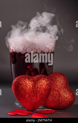 Cocktail de Saint-Valentin avec glace sèche sur fond sombre Banque D'Images