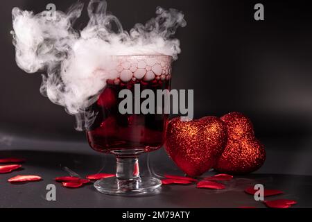 Cocktail de Saint-Valentin avec glace sèche sur fond sombre Banque D'Images