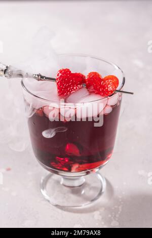 Cocktail de Saint-Valentin avec glace sèche sur fond sombre Banque D'Images