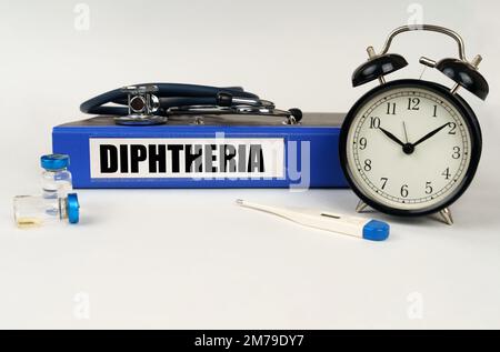 Concept médical. Sur une surface blanche, un thermomètre, des ampoules, un stéthoscope, un réveil et un dossier avec l'inscription « diphtérie » Banque D'Images