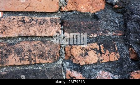 Gros plan de vieux mur de briques, avec les briques altérées et couvertes de saleté noire. Banque D'Images