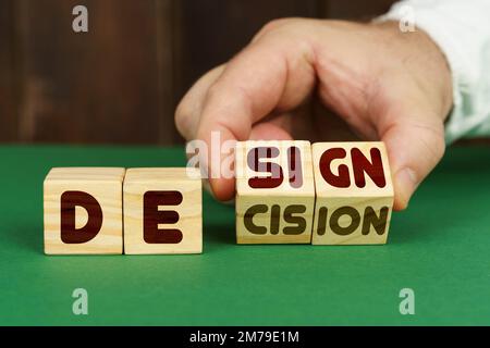 Concept d'entreprise. Sur une surface verte, un homme met des cubes avec l'inscription - Design, Decision Banque D'Images