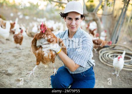 Agricultrice tenant du poulet dans une ferme avicole Banque D'Images