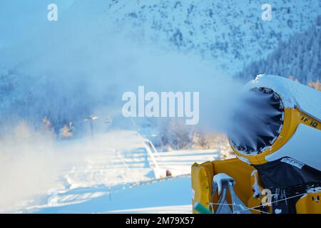 Canons à neige dans les montagnes d'hiver. Pistolet à neige pulvérisant des cristaux de glace artificiels. Machine faisant de la neige Banque D'Images