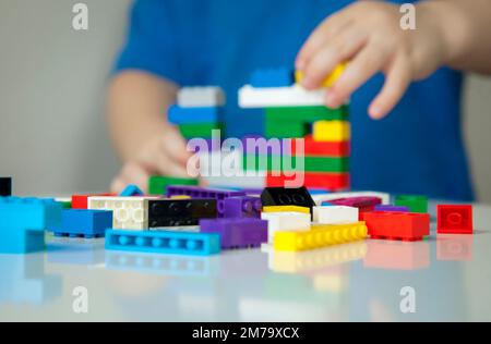 Garçon joue des cubes multicolores et des voitures sur la table. Développement et apprentissage précoces. Banque D'Images