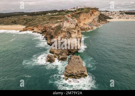 Vue aérienne d'un phare sur une falaise avec une forteresse dans la ville de Nazaré, Portugal Banque D'Images