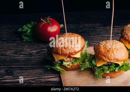 Deux délicieux hamburgers faits maison avec de la viande, du fromage, de la laitue, de la tomate sur une table en bois Banque D'Images