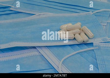 Une pile de pilules blanches repose sur des masques médicaux bleus (gros plan). Médecine moderne. Traitement des maladies. Pas de covid Banque D'Images