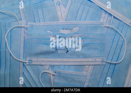 Utilisé (brûlé) masque médical bleu sur le fond de nouveaux masques (non utilisés). Le concept de la fin de la pandémie. Annuler le mode masque. Zéro covi Banque D'Images