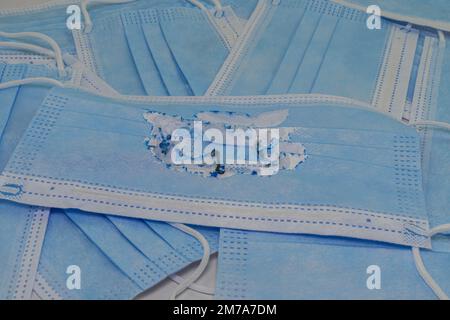 Utilisé (brûlé) masque médical bleu sur le fond de nouveaux masques (non utilisés). Le concept de la fin de la pandémie. Annuler le mode masque. Zéro covi Banque D'Images