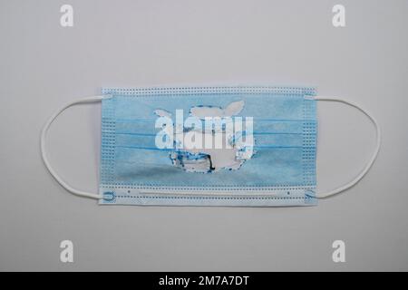 Utilisé (brûlé) masque médical bleu isolé sur fond gris. Le concept de la fin de la pandémie. Annuler le mode masque. Zéro covid Banque D'Images