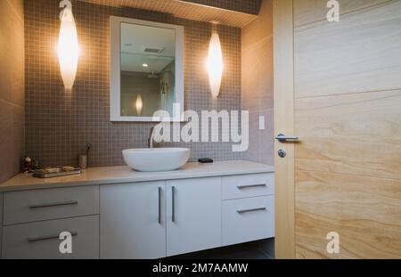 Évier de bol en porcelaine blanche et vanité laquée, miroir dans la salle de bain d'invités à l'étage à l'intérieur de la maison de style cubiste moderne. Banque D'Images