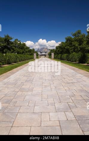 Allée en pierre pavée avec des colonnes en pierre bordées par Miscanthus - plantes ornementales d'herbe menant à l'élégante maison en pierre grise Banque D'Images