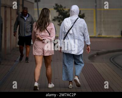 Photo de deux filles marchant dans les rues de Szeged, en Hongrie, l'une avec des vêtements courts, l'autre portant un foulard islamique, un hijab. Banque D'Images