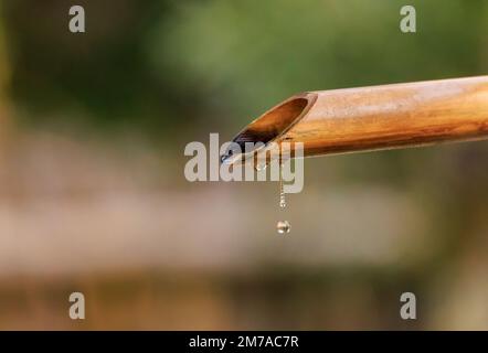 Gros plan gouttes d'eau tombant de la pipe traditionnelle de bambou Banque D'Images