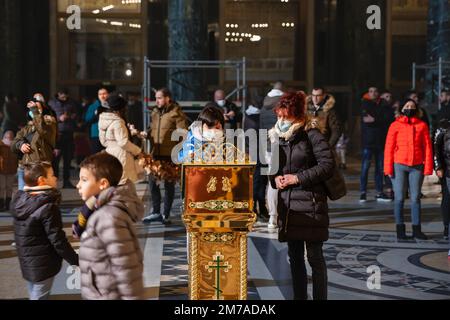 Photo d'une famille blanche caucasienne priant en portant un masque de Noël dans l'église orthodoxe du temple de Saint Sava tout en portant un protectiv Banque D'Images