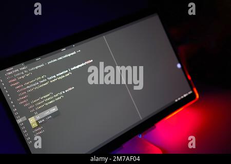 Écriture du code de l'ordinateur affiché sur le rétroéclairage rouge néon du moniteur Banque D'Images