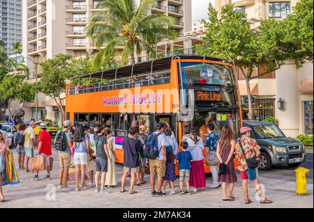 Honolulu, Hawaï - 29 décembre 2022 : le tramway de Waikiki qui prend les touristes sur l'avenue Kalakaua. Banque D'Images