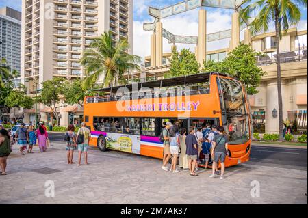 Honolulu, Hawaï - 29 décembre 2022 : le tramway de Waikiki qui prend les touristes sur l'avenue Kalakaua. Banque D'Images