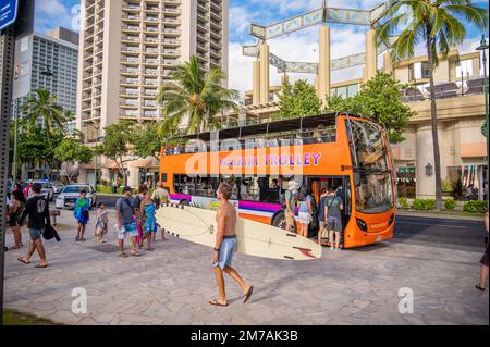 Honolulu, Hawaï - 29 décembre 2022 : le tramway de Waikiki qui prend les touristes sur l'avenue Kalakaua. Banque D'Images