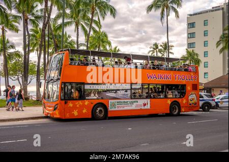 Honolulu, Hawaï - 29 décembre 2022 : le tramway de Waikiki qui prend les touristes sur l'avenue Kalakaua. Banque D'Images